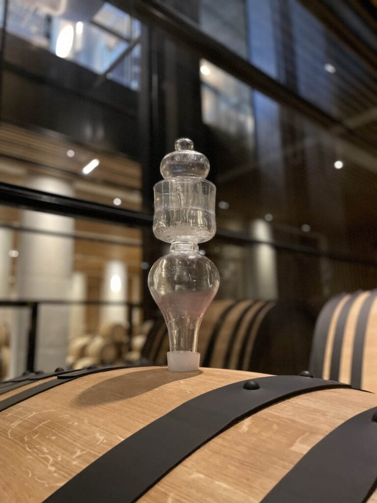 Glasstopfen an einem Eichenfass im modernen Weingut Château Pédesclaux in Pauillac, Bordeaux, Grand Cru Classé des Médoc, für die Vinifizierung und Reifung großer Weine.