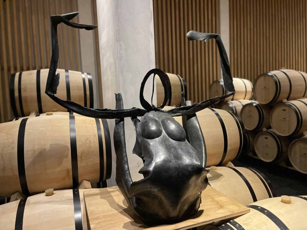 Zeitgenössische Skulptur aus schwarzem Metall im Weinkeller von Château Pédesclaux in Pauillac, umgeben von Eichenfässern zur Reifung von Weinen, Grand Cru Classé aus dem Médoc, Bordeaux.