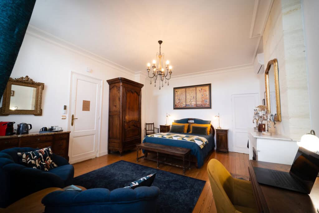 Grande chambre Domeyne de 27 m² au Château Papounan, avec lit 160x200 en linge de lin, fauteuils détente, bureau et décoration rétro dans une chambre d’hôtes de charme à Saint-Estèphe, Médoc.