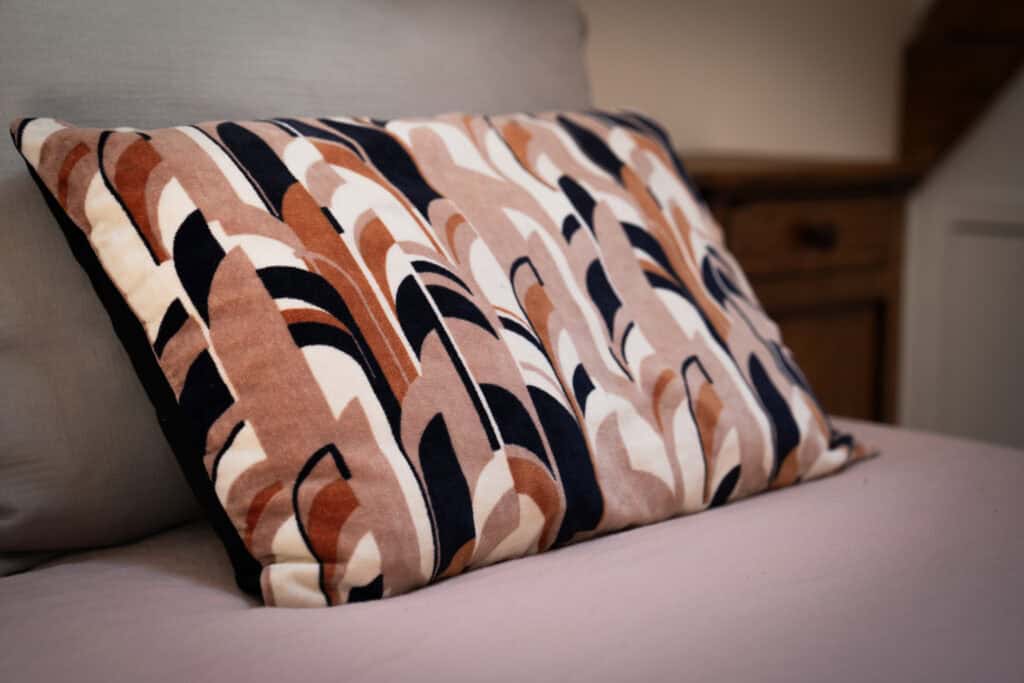 Coussin décoratif aux motifs géométriques dans la Suite l’Estuaire du Château Papounan, chambre d’hôtes de charme à Saint-Estèphe, Médoc.