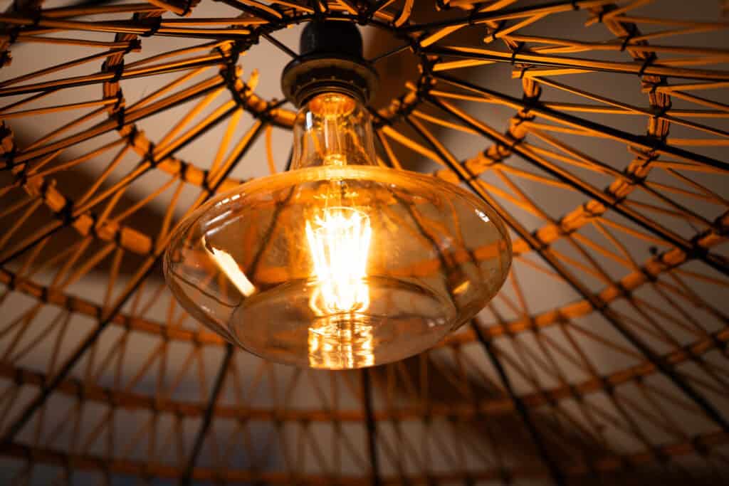 Détail décoratif : suspension en rotin avec ampoule rétro dans la Suite l’Estuaire du Château Papounan, chambre d’hôtes de charme à Saint-Estèphe, Médoc.