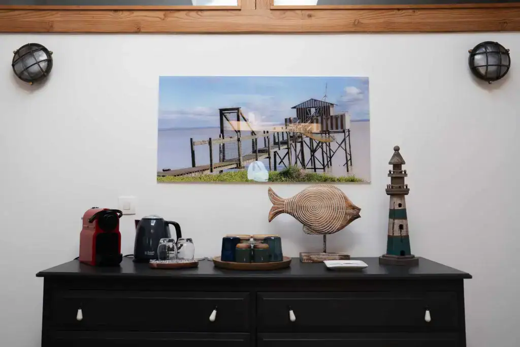 Eine Nespresso-Maschine, ein Wasserkocher und Geschirr auf einer mit maritimen Elementen verzierten Kommode in der Suite l’Estuaire im Château Papounan, einem charmanten Bed & Breakfast in Saint-Estèphe, Médoc.
