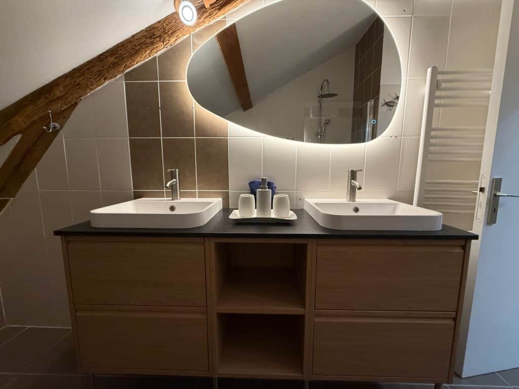 Salle de bain élégante avec doubles vasques, miroir rétro-éclairé et douche thermostatique dans la Suite l’Estuaire du Château Papounan, chambre d’hôtes de charme à Saint-Estèphe, Médoc.