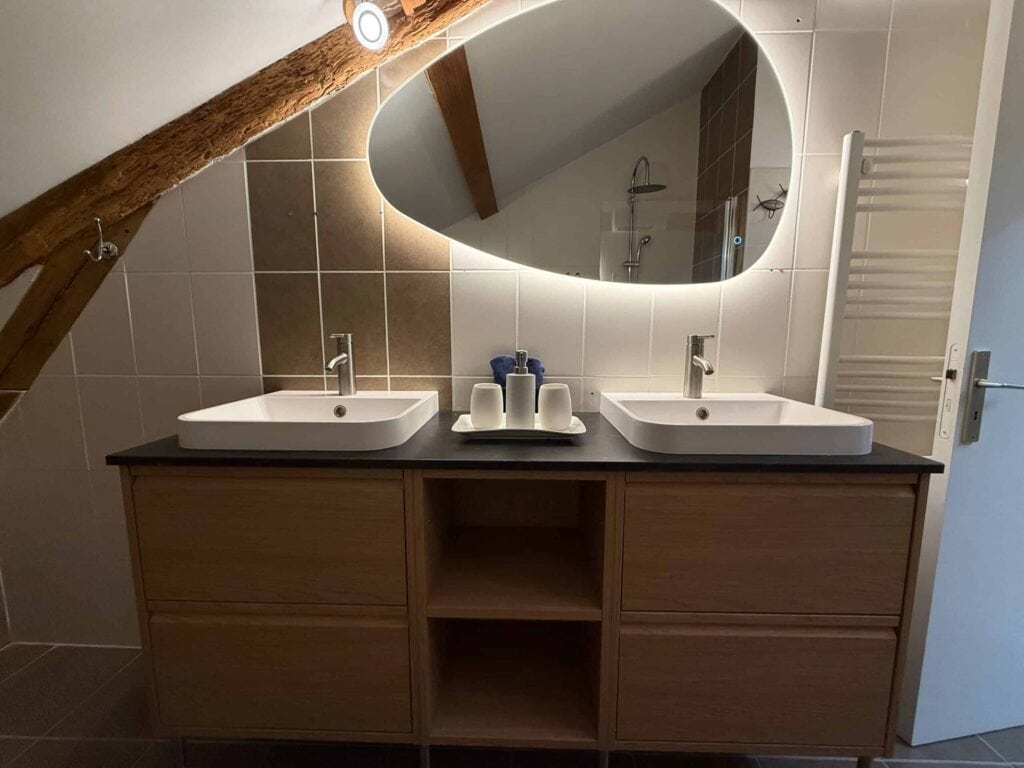 Elegantes Badezimmer mit Doppelwaschbecken, hinterleuchtetem Spiegel und Thermostatdusche in der Suite l’Estuaire im Château Papounan, einem charmanten Bed & Breakfast in Saint-Estèphe, Médoc.