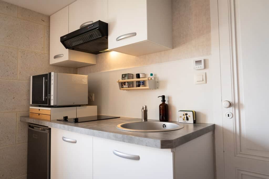 Kitchenette avec plaque de cuisson, micro-ondes combiné et évier dans le Studio Les Vignes du Château Papounan, chambre d’hôtes de charme à Saint-Estèphe, Médoc.