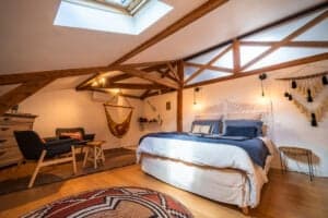 Large Océane Suite of 40 m² with exposed beams, 160x200 bed in linen, suspended hammock and relaxation area at Château Papounan, charming guest rooms in Saint-Estèphe, Médoc.