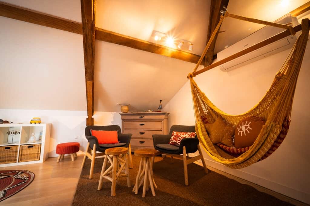 Coin détente avec hamac jaune, fauteuils confortables et table basse en bois dans la Suite Océane du Château Papounan, chambre d’hôtes de charme à Saint-Estèphe, Médoc.