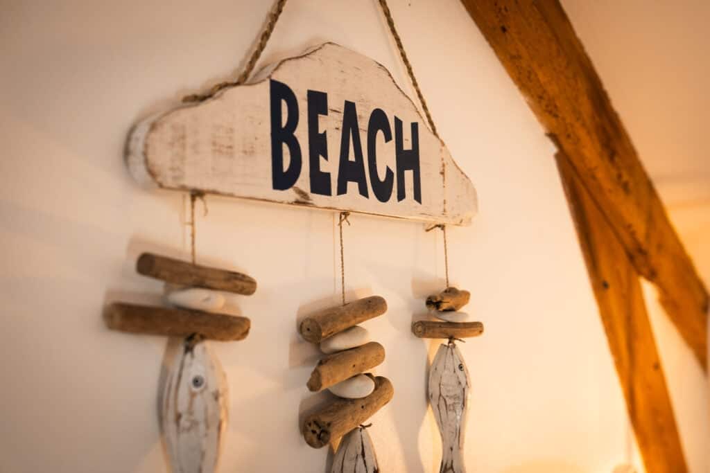 Panneau décoratif « BEACH » en bois patiné avec suspensions en bois flotté et poissons, dans la Suite Océane du Château Papounan, chambre d’hôtes de charme à Saint-Estèphe, Médoc.