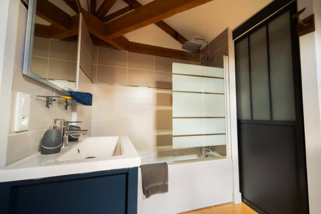 Salle de bain privative avec baignoire, douche thermostatique et meuble vasque dans la Suite Océane du Château Papounan, chambre d’hôtes de charme à Saint-Estèphe, Médoc.