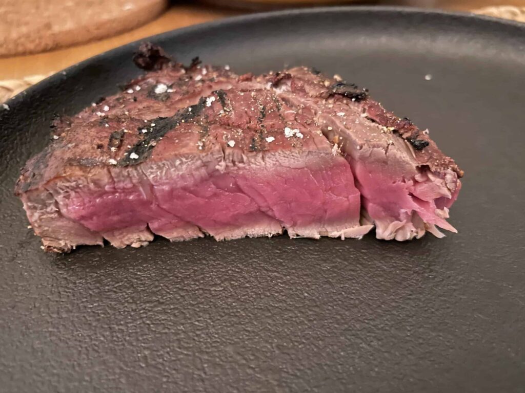 Entrecôte cuite à la perfection, saignante et rosée, servie sur une assiette noire