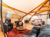 Vue intérieure de la Suite l’Estuaire avec lit queen-size, coin salon, poutres apparentes et décoration raffinée au Château Papounan, chambre d’hôtes de charme à Saint-Estèphe, Médoc.