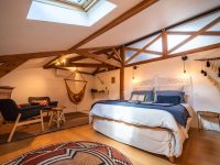 Grande Suite Océane de 40 m² avec poutres apparentes, lit 160x200 en linge de lin, hamac suspendu et coin détente au Château Papounan, chambres d’hôtes de charme à Saint-Estèphe, Médoc.